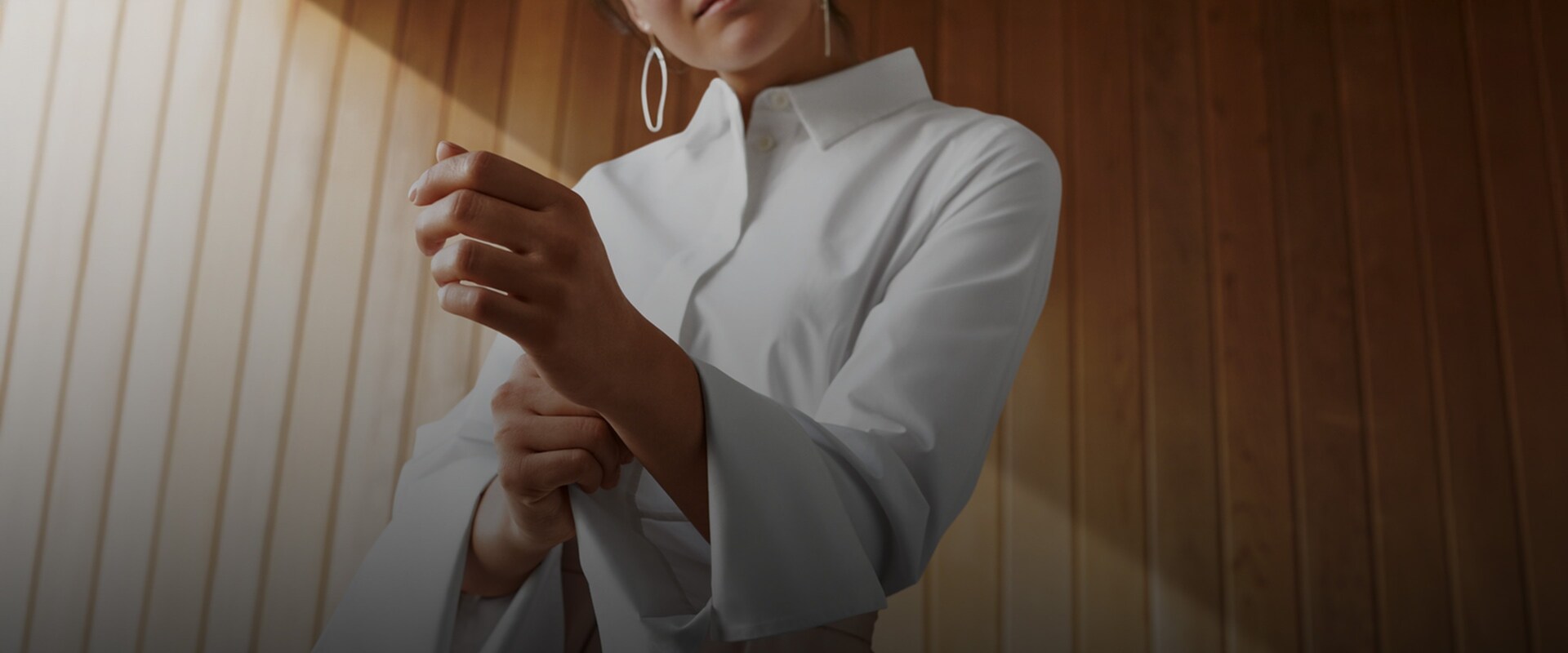 Nainen taittelee valkoisen paitansa hihan.